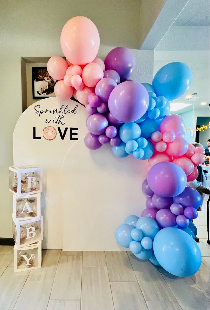 the balloon arch is decorated with pink, blue and purple balloons