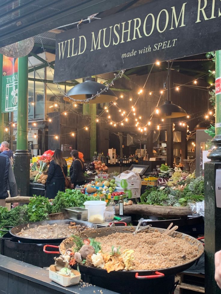 people are standing in front of a store with lots of food on the tables and outside