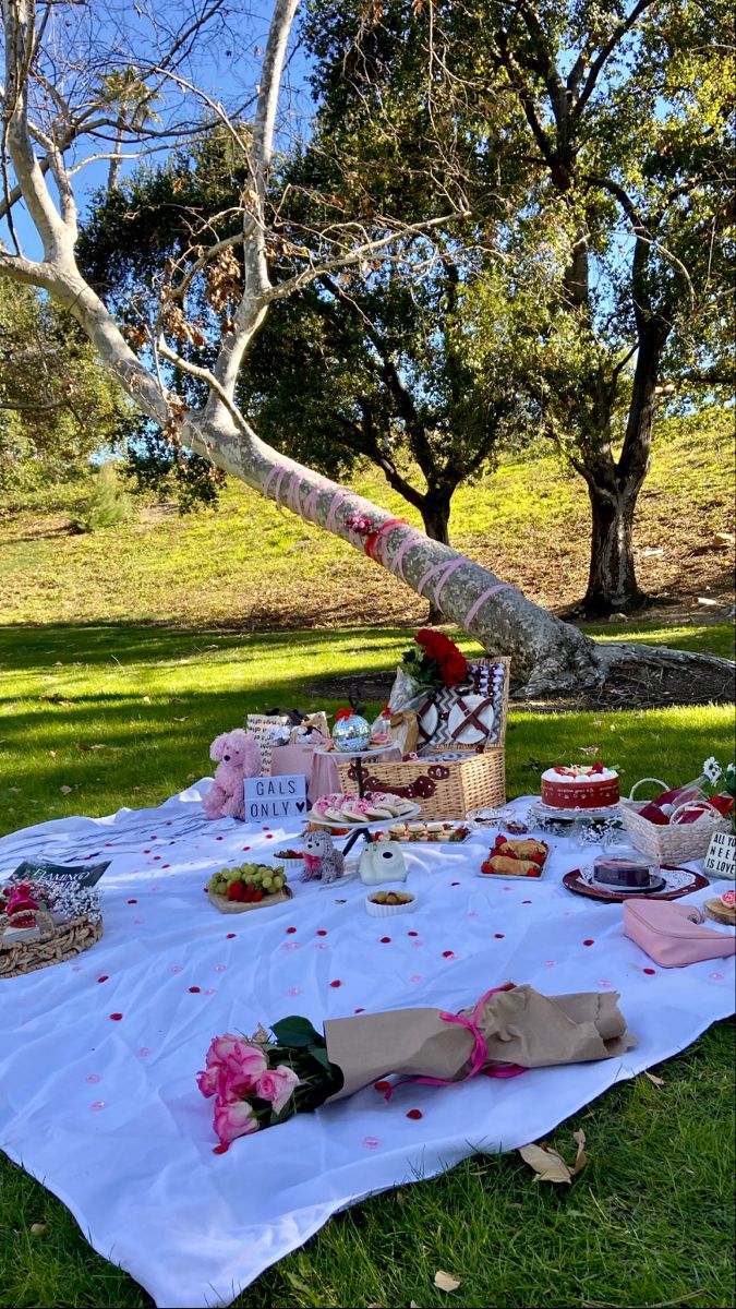 a picnic table set up in the grass with food on it and flowers all around