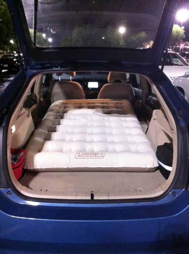 the back end of a blue car with an inflatable mattress