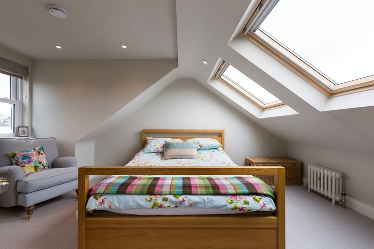 an attic bedroom with a bed, chair and couch in it's center area