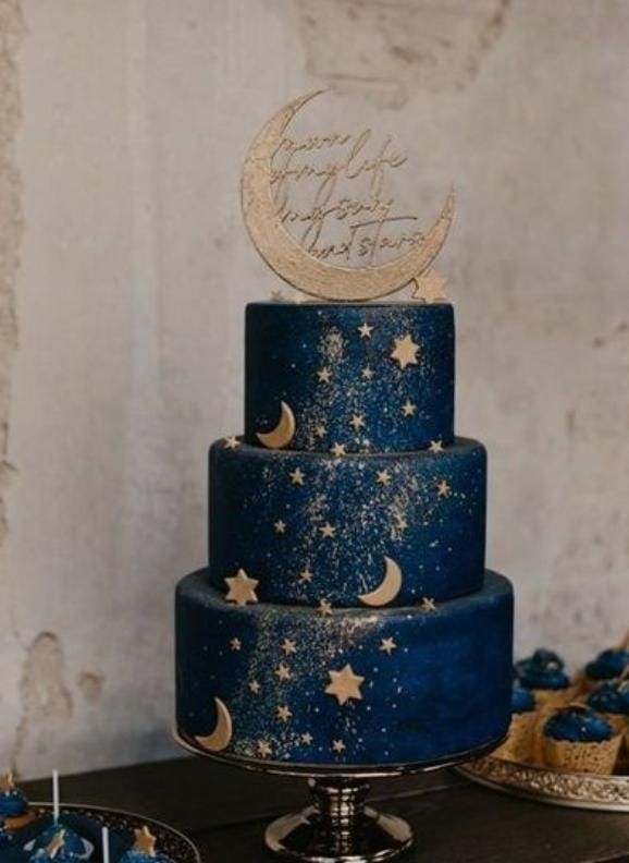 a three tiered blue cake with stars and moon decorations