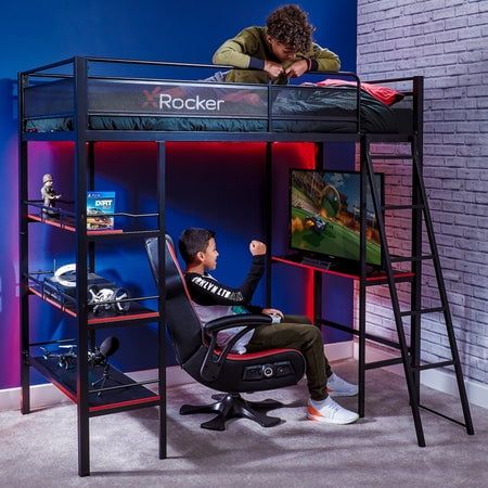 a young boy sitting on top of a bunk bed next to a gaming desk and chair