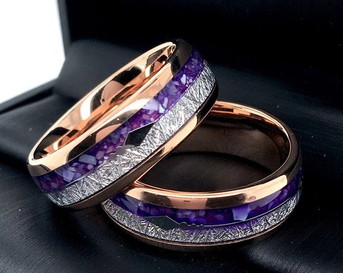 two wedding bands with purple and white stones in them on a black surface next to each other