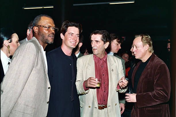 three men standing next to each other at an event with one holding a drink in his hand