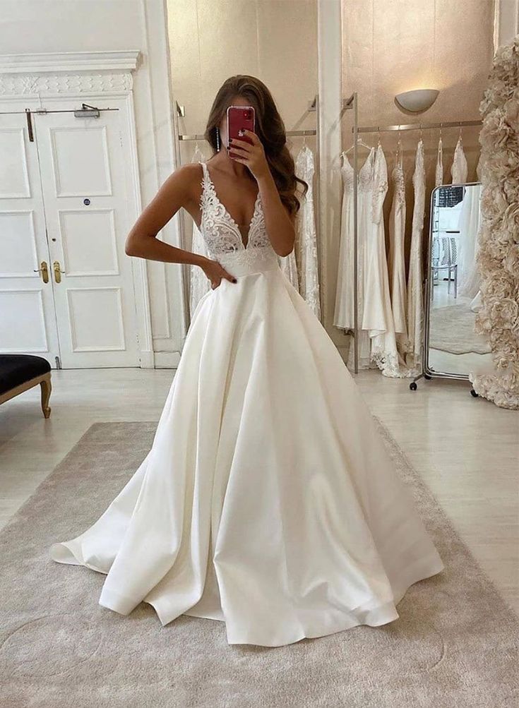 a woman in a wedding dress taking a selfie with her cell phone while looking into the mirror