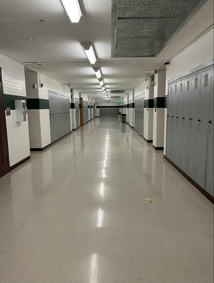 an empty hallway with several lockers on the walls and doors to other rooms in it