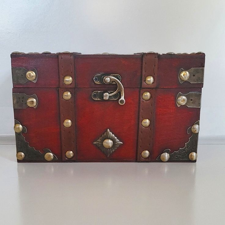 a red leather box with brass hardwares on the front and sides is sitting on a white surface