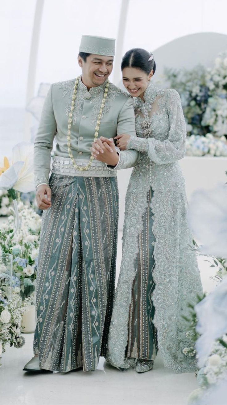 two people standing next to each other in front of flowers