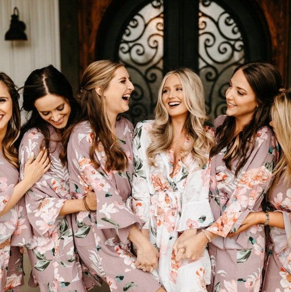 a group of women standing next to each other wearing matching robes and smiling at the camera