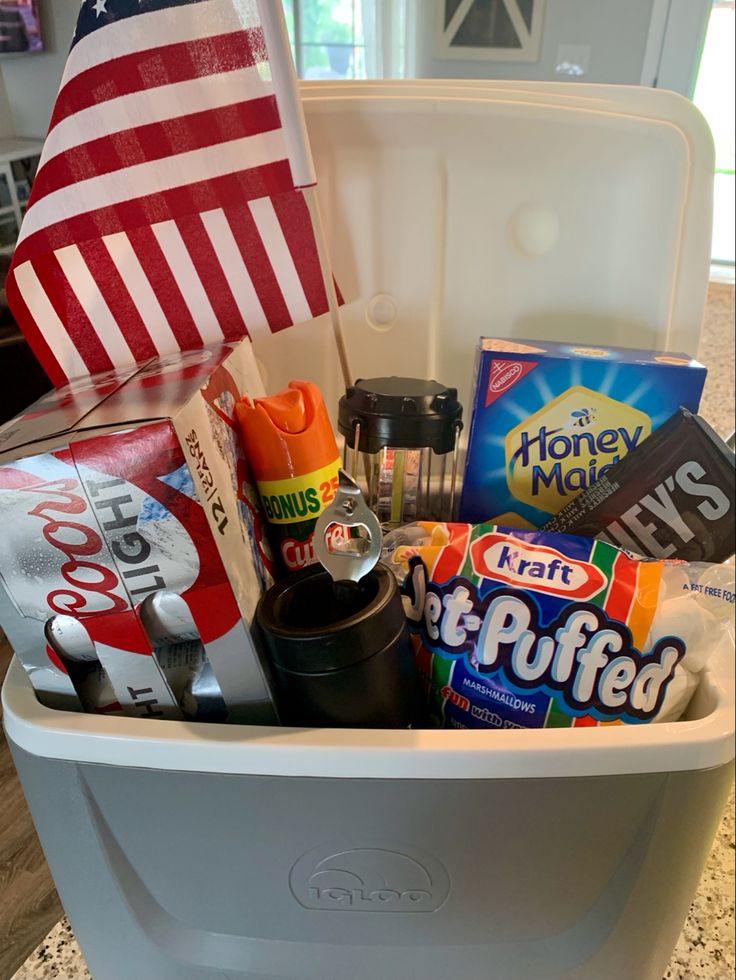 a cooler filled with snacks and other items on top of a granite counter next to an american flag