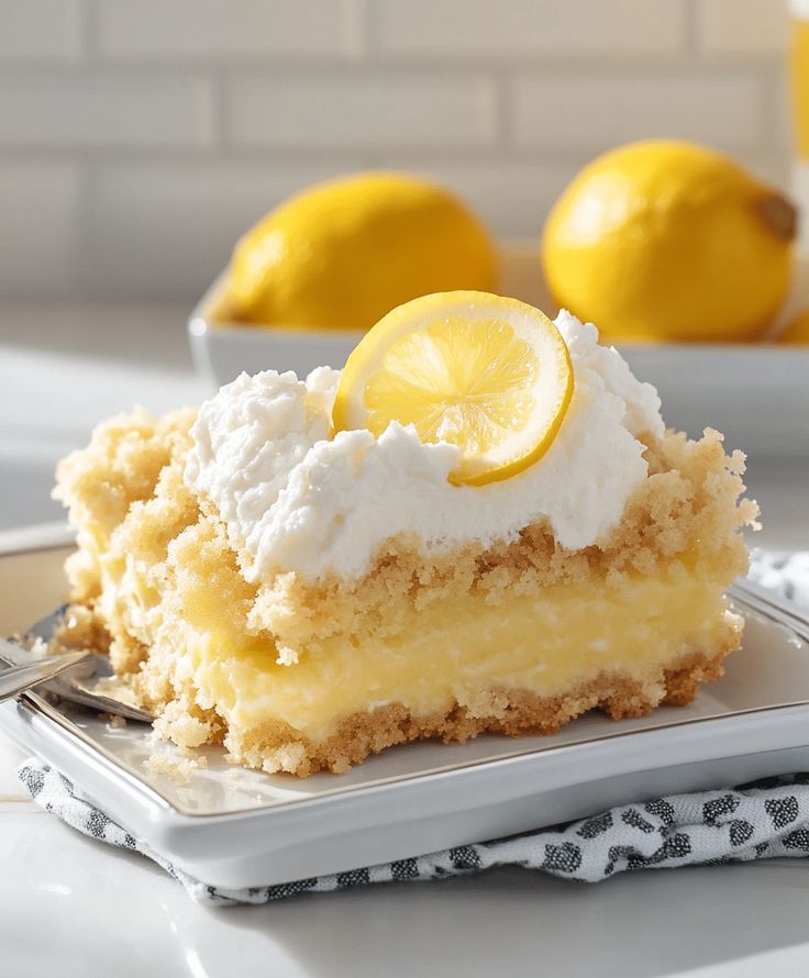 a slice of lemon cake on a plate with two lemons in the background