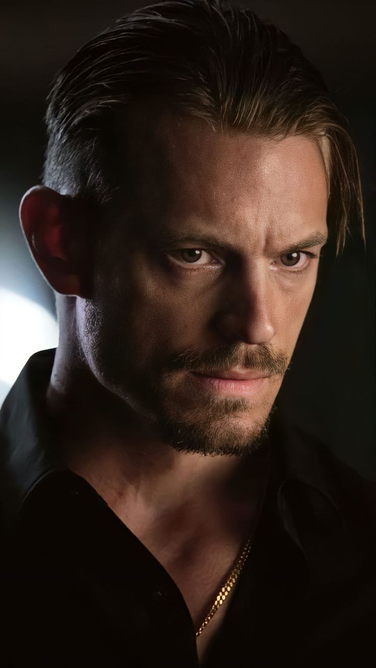 a close up of a person wearing a black shirt and looking at the camera with a serious look on his face