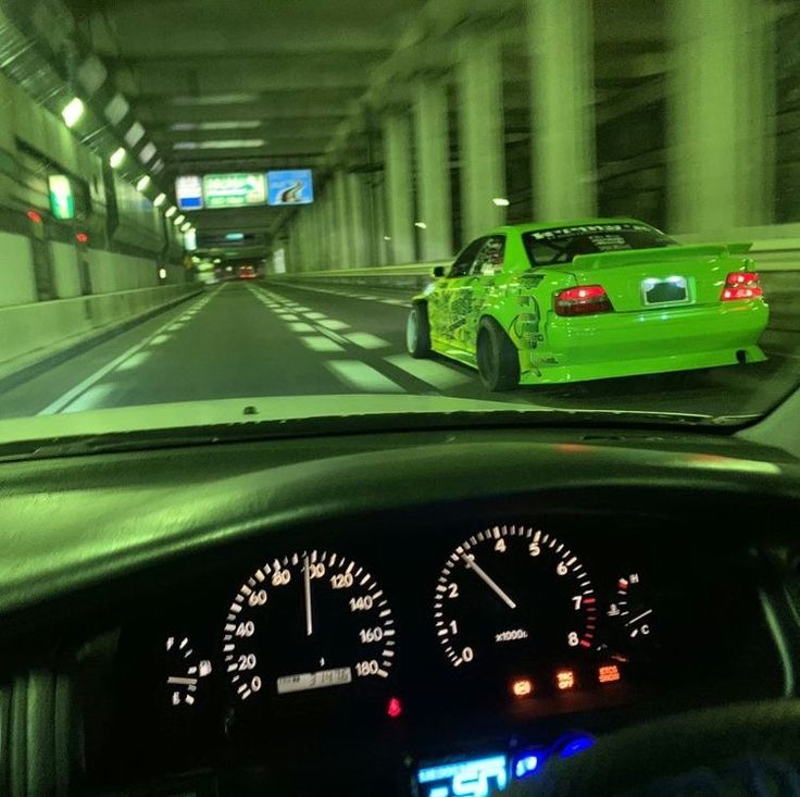 a green car driving through a tunnel