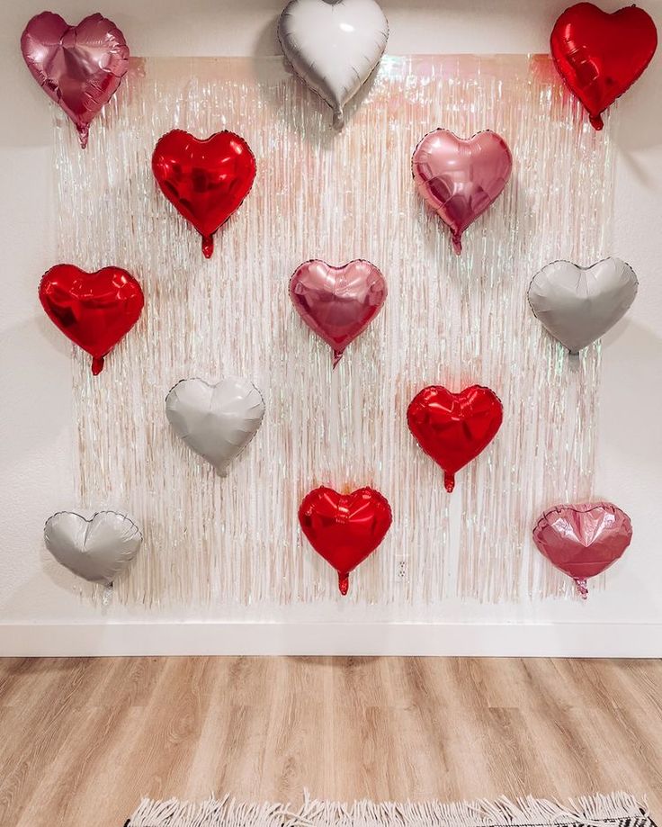 heart shaped balloons are hanging on the wall in front of a white and red backdrop