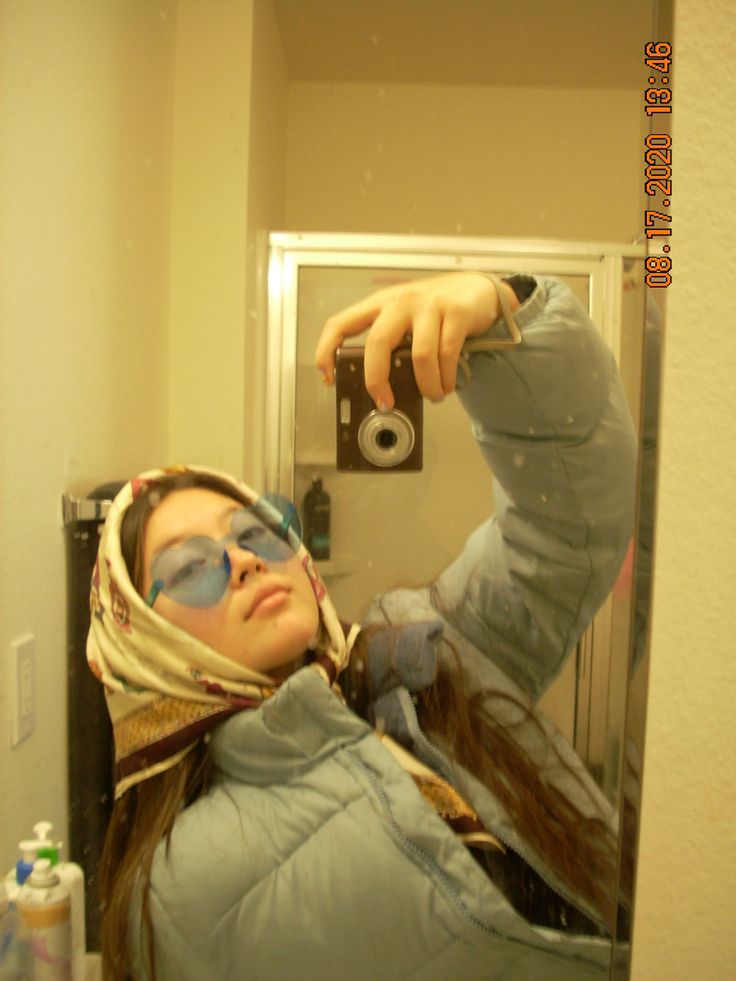 a woman taking a selfie in front of a mirror with her hand on the camera