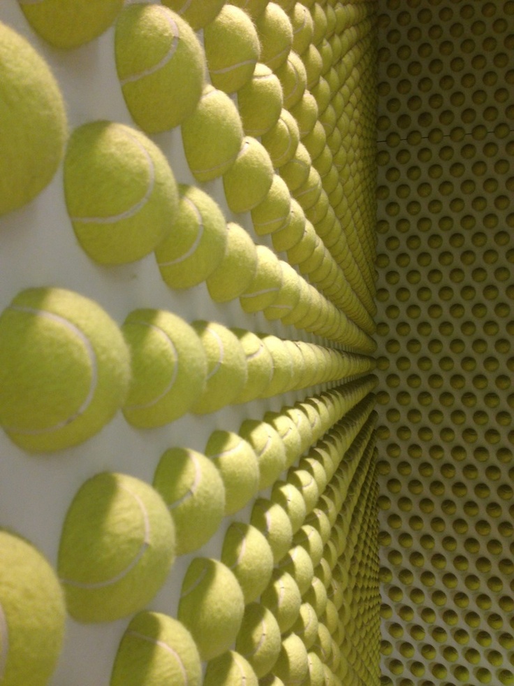 the tennis balls are all arranged in a spiral pattern on the wall, and they appear to be made out of paper