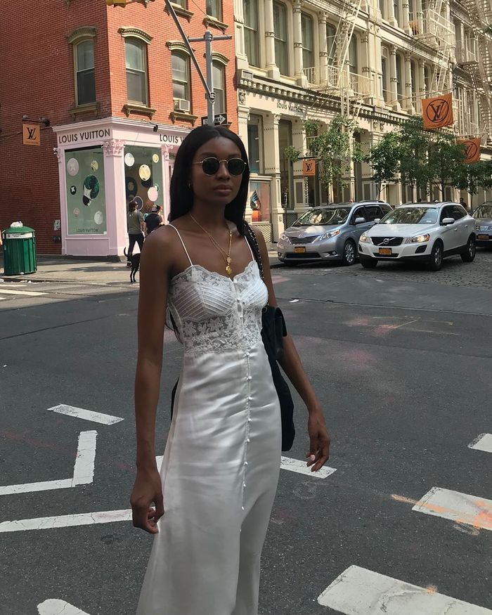 a woman in a white dress is crossing the street