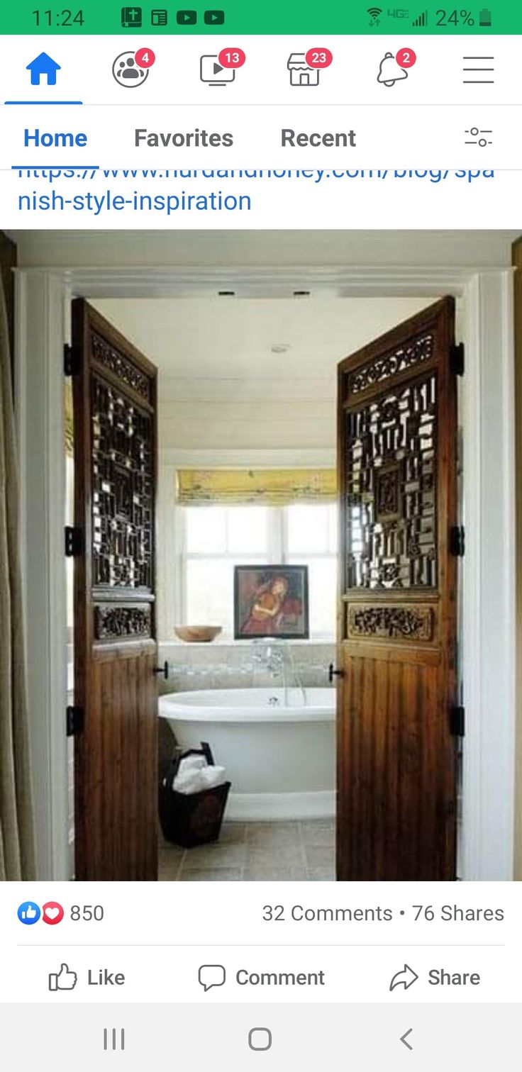 an open door leading to a bathroom with a tub in the middle and pictures on the wall