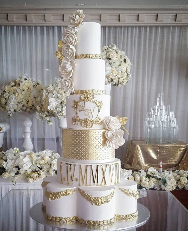 a white and gold wedding cake with flowers