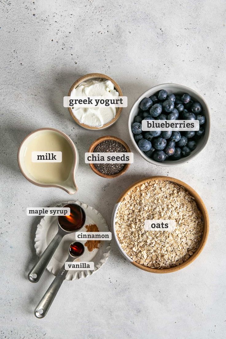 ingredients for blueberry chia seed pudding laid out in bowls on a white surface