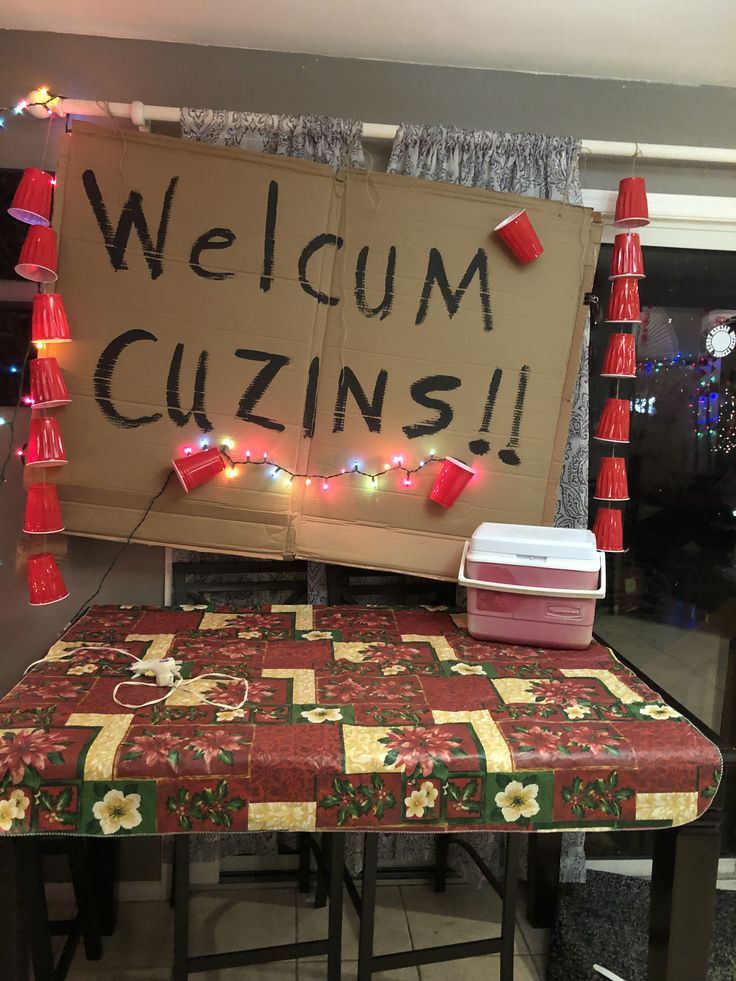 a sign that says welcome to cuzns on the side of a table with lights around it