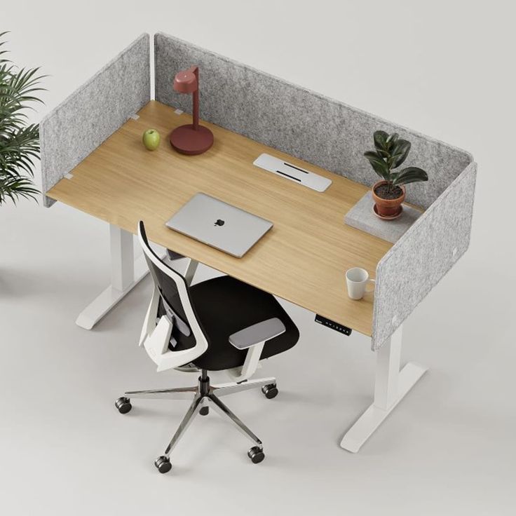 an office cubicle with a desk, chair and laptop on it in front of a potted plant