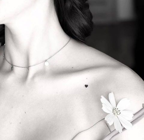 a woman wearing a necklace with a flower on the back of her shoulder and neck