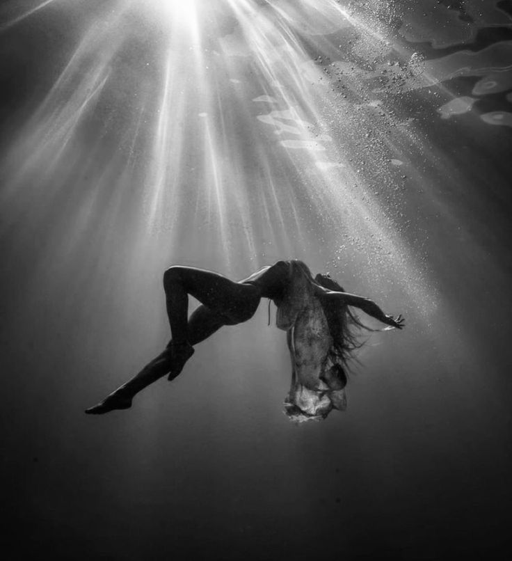 a woman is floating in the water with sunbeams above her head and body