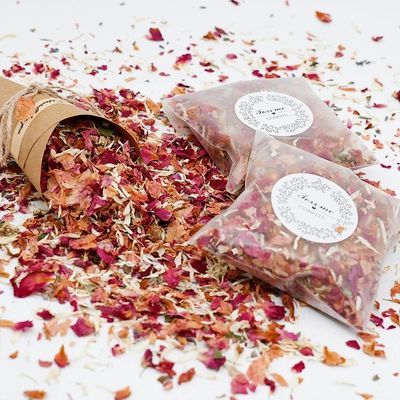 three bags filled with dried flowers on top of a white tablecloth covered in confetti