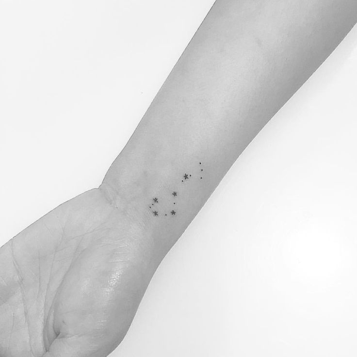 a person's wrist with small stars on the left side of their arm and an ink spot in the middle