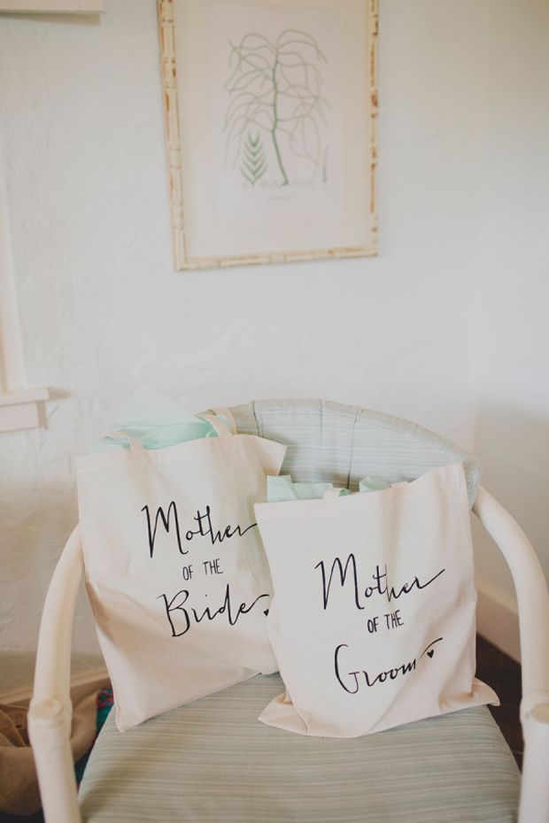 two totes are sitting on a chair in front of a framed picture with the words mother of the bride and groom written on them