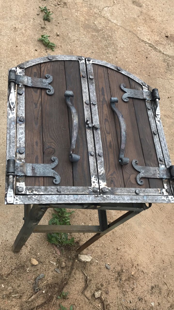 an old wooden bench with metal straps on it's sides and some weeds growing in the dirt