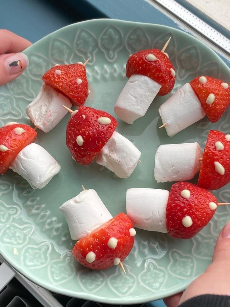 strawberries and marshmallows are arranged on skewers