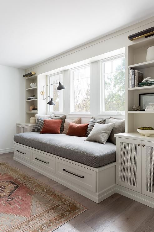 a living room filled with lots of furniture and bookshelves next to a window