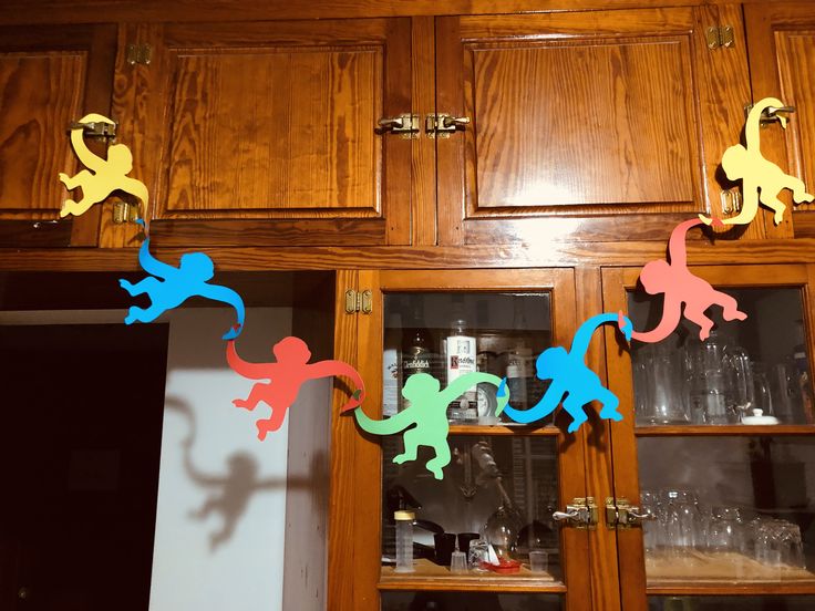 colorful paper cutouts are hanging from the cabinets in this kitchen area, which is decorated with wooden cupboards and glassware