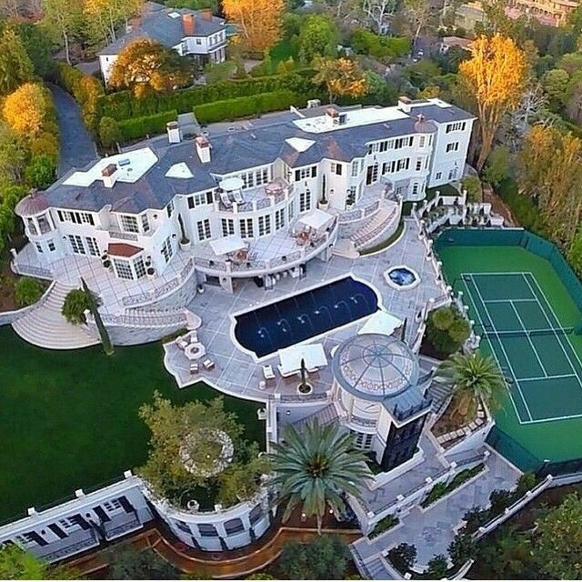 an aerial view of a large mansion with tennis court