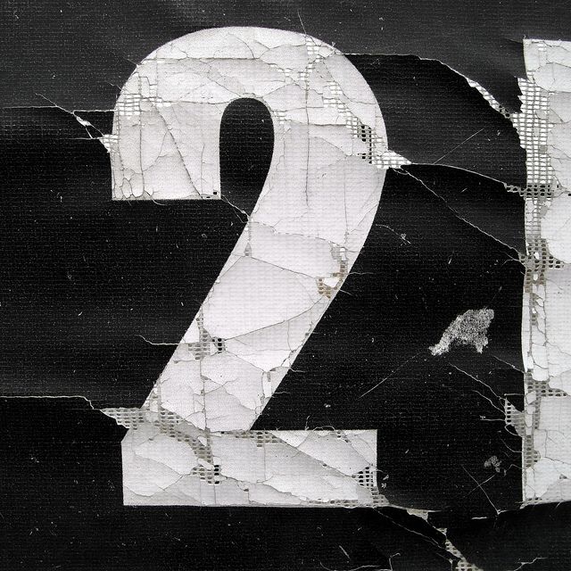 the number twenty two is written in white paint on black paper with torn up edges