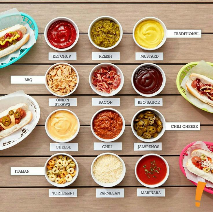 several different types of hot dogs and condiments in bowls on a wooden table