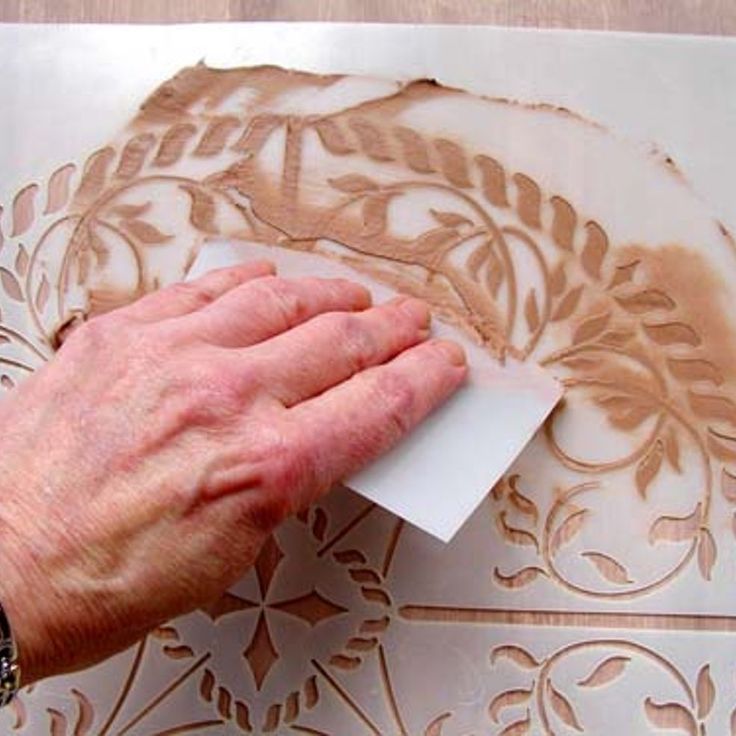 a person is using a piece of paper to cut out decorative designs on a wall