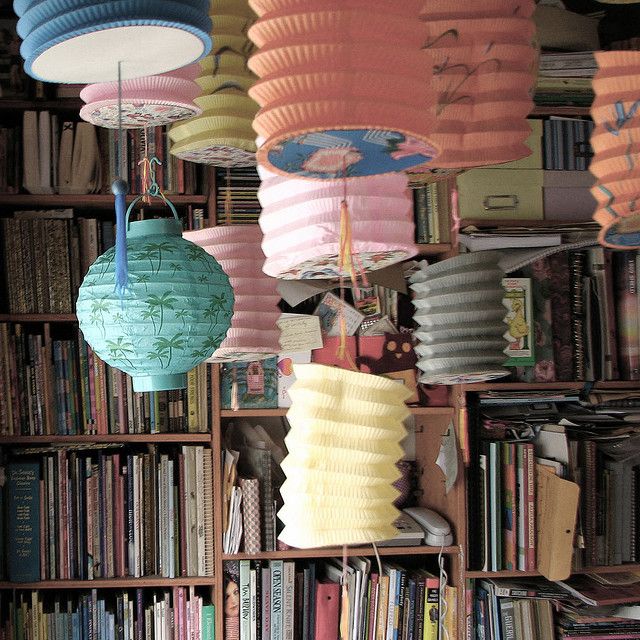 several paper lanterns hanging from the ceiling in a room with bookshelves and shelves