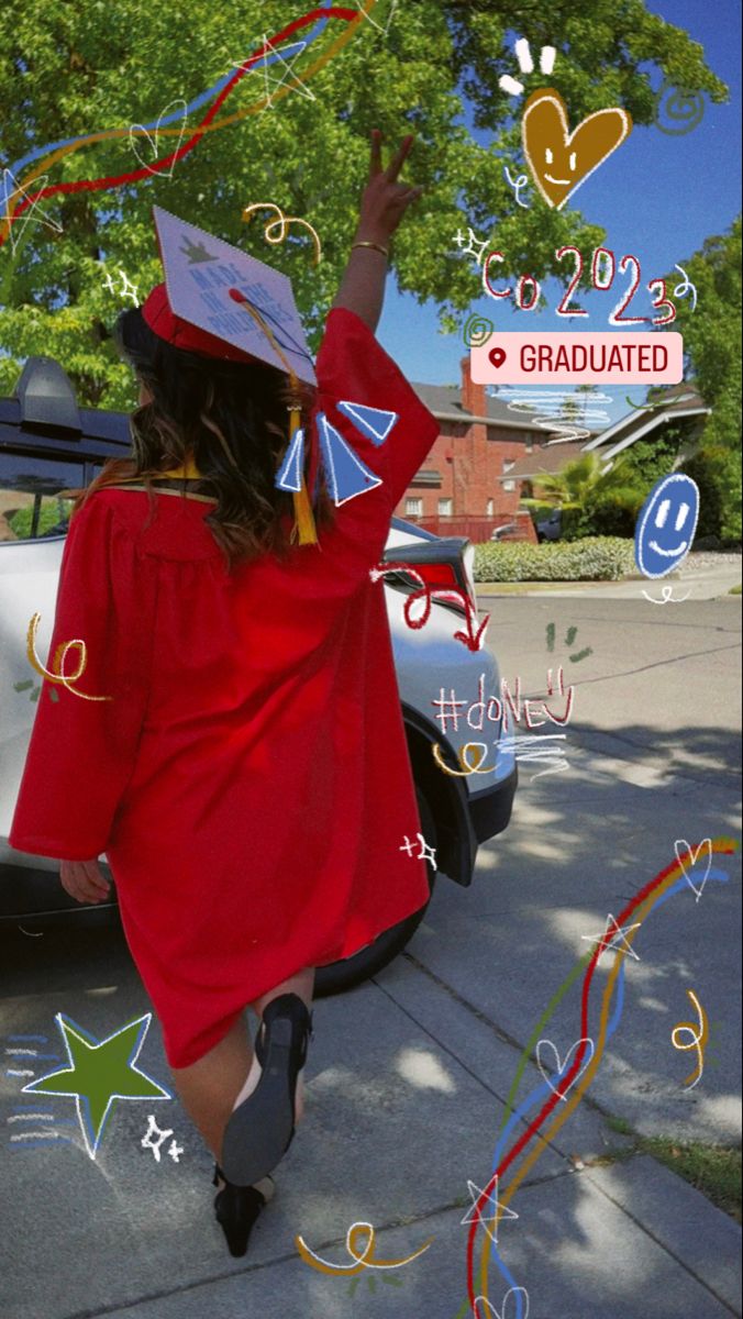 a girl in red graduation gown and cap walking down the street with her hand up