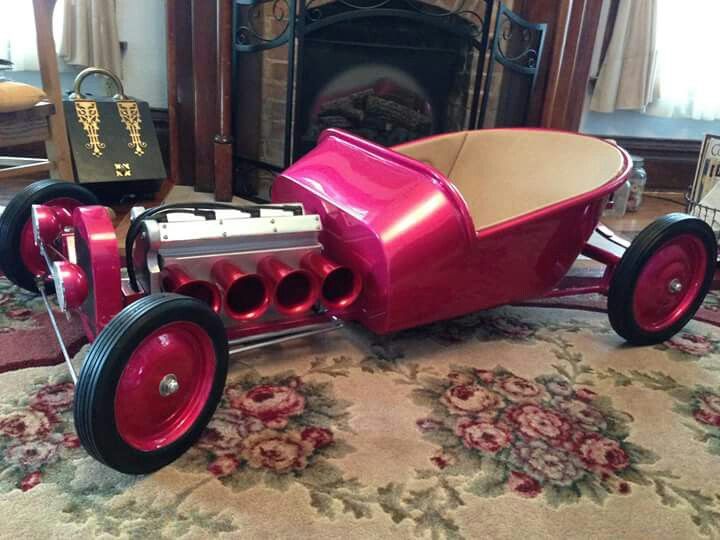 a red toy car sitting on top of a rug in front of a fire place