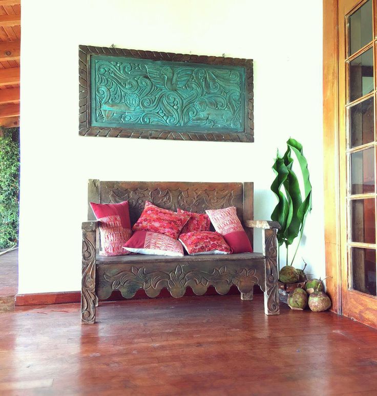 a wooden bench sitting in the middle of a living room next to a green plant