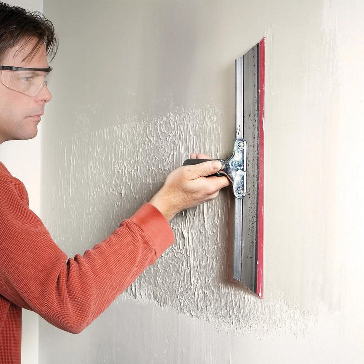 a man in glasses is working on a wall