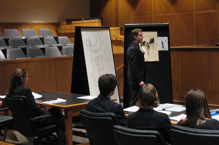 a man standing in front of a group of people at a table with papers on it