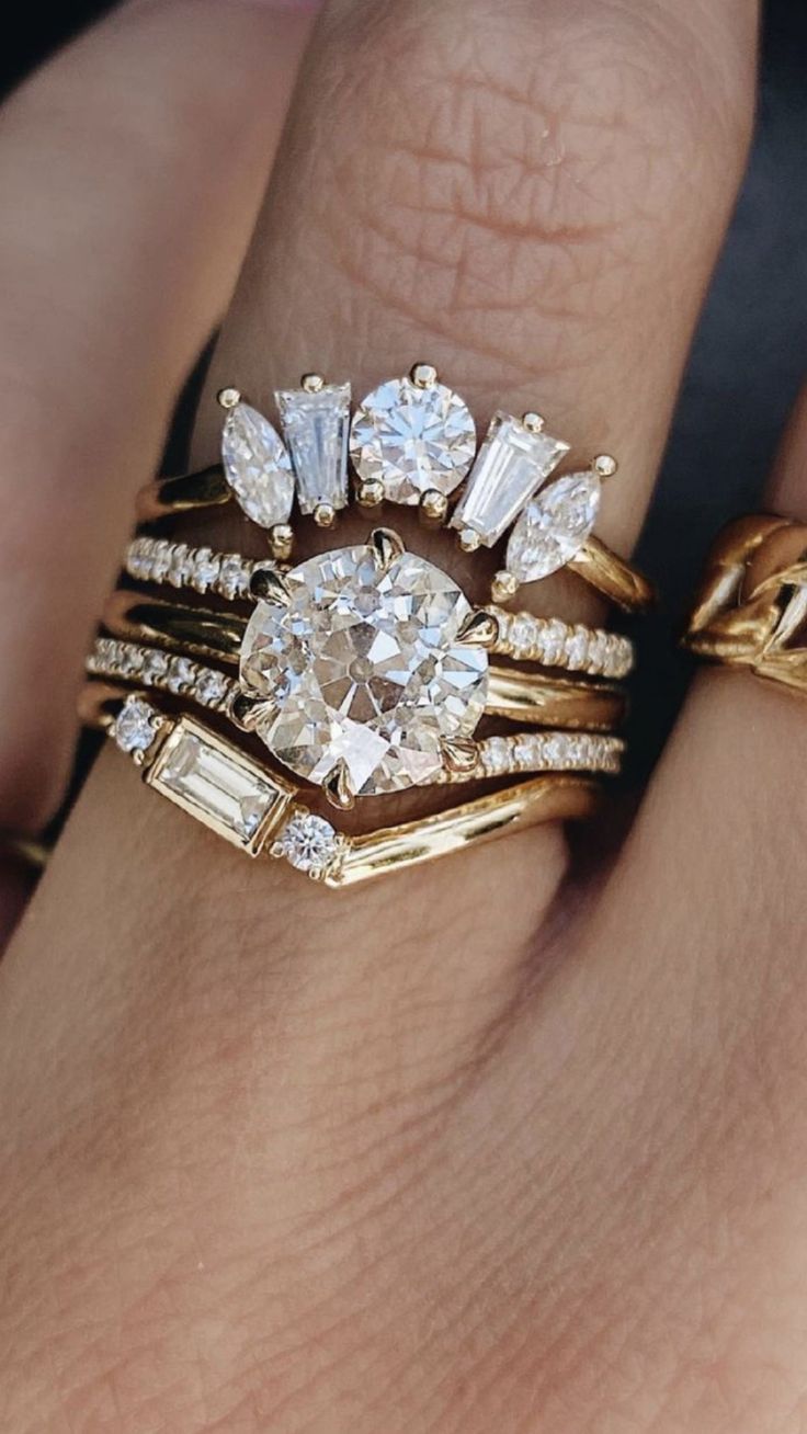 a woman's hand with two gold rings on it and an engagement ring in the middle