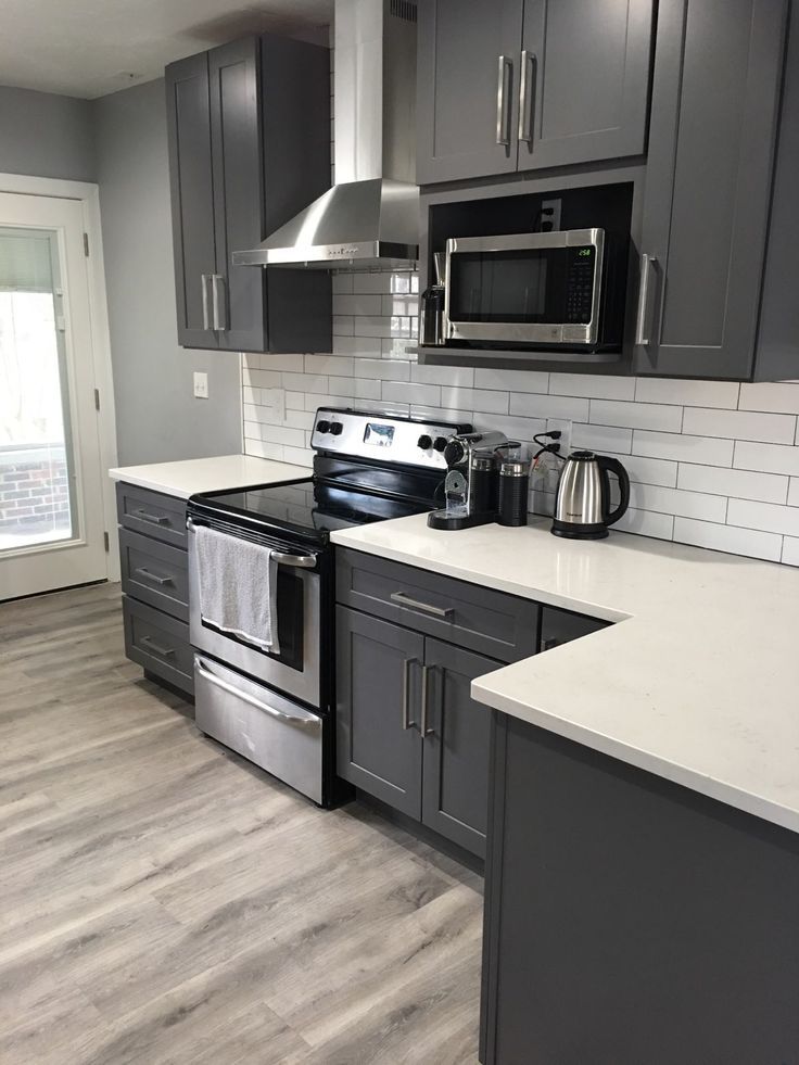 a kitchen with gray cabinets and stainless steel appliances