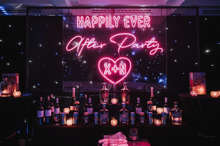 a neon sign that says happily ever after party with lit candles in front of it