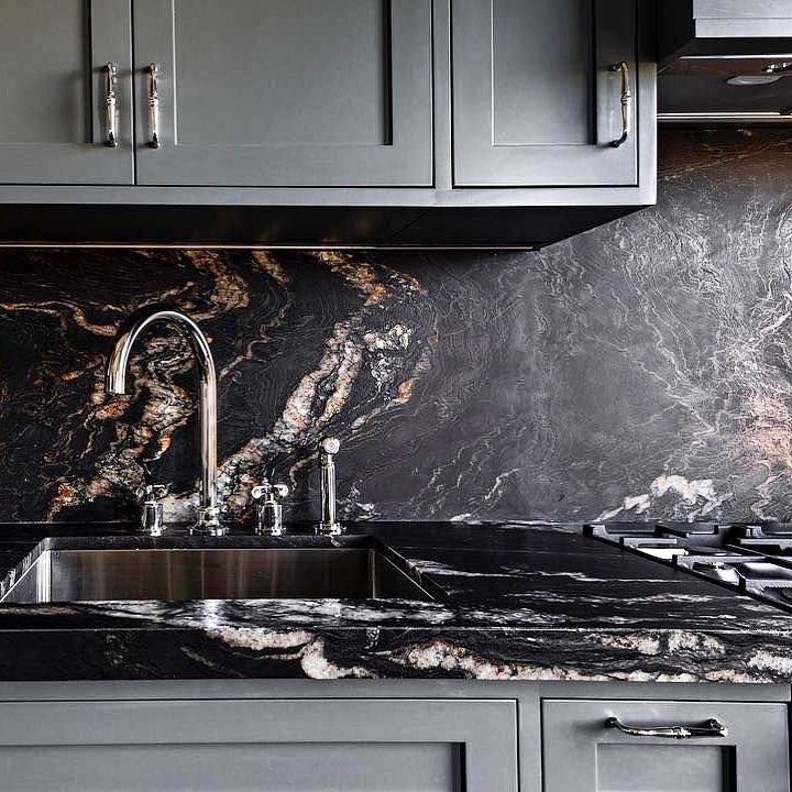 a kitchen with marble counter tops and gray cabinets